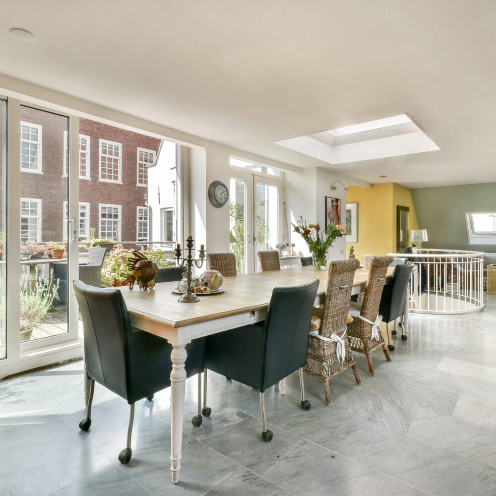 Bright and airy interior featuring a stylish dining area with elegant furniture and large windows overlooking a vibrant outdoor space.