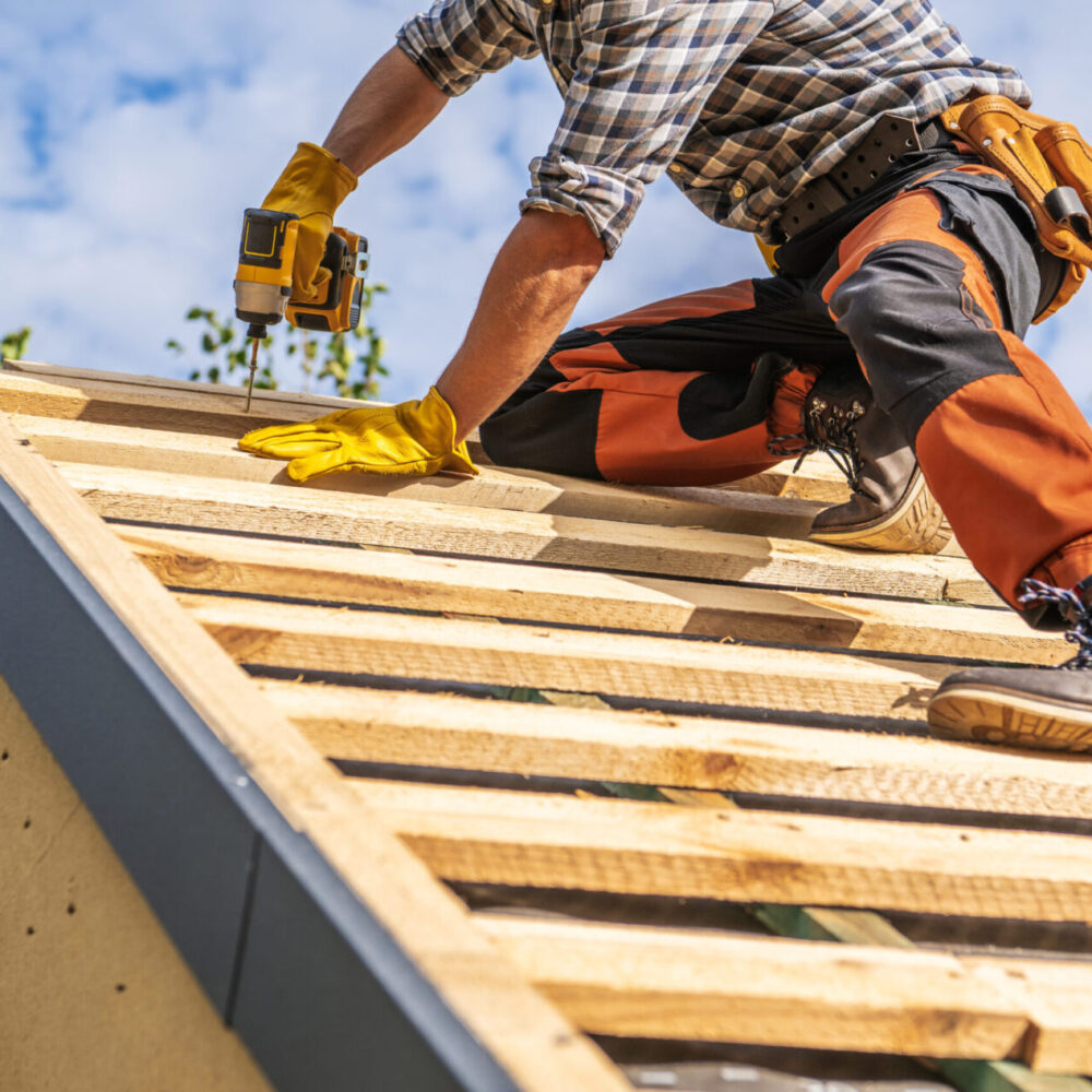 Caucasian Professional Roofing Contractor in His 40s Attaching Wooden Elements to the House Roof